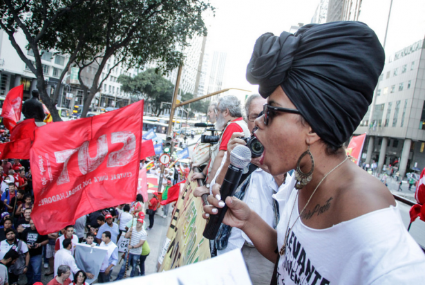 Banderas de la Coalición del Sindicato de los Trabajadores o CUT ondean en la multitud cuando el portavoz de la facción de jóvenes del Movimiento de los Sin Tierra, Levante Popular, habla en la marcha en contra de la destitución en Río de Janeiro el 20 de agosto (Mídia NINJA)