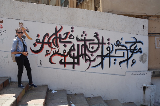 Hayat Chaaban stands next to one of her murals in Tripoli. (WNV/