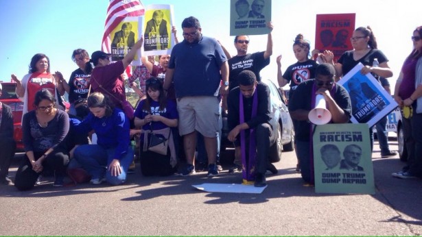Members of Puente Arizona pray together as they put their bodies on the line to block access to a Trump rally. (Twitter / Puente Arizona)
