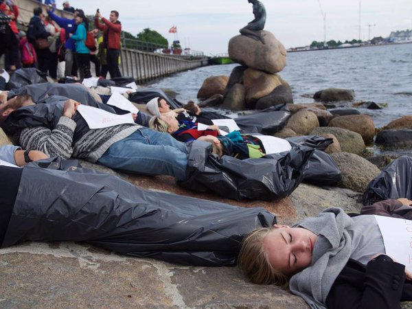 Danish activists stage a scene depicting a dead boat of refugees next to The Little Mermaid Statue in Copenhagen. (Twitter / @FlygtningeInfo)