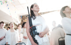 A woman dressed in white holds an AR-15 rifle during a church ceremony.