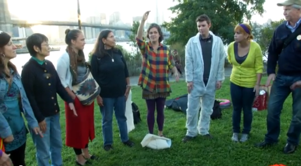 Artist Rachel Schragis leads a group of climate activists in a song about unity. (Youtube still / Owen Crowley)