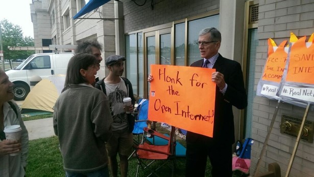 FCC Chair Tom Wheeler holding a sign when he came out to meet activists at the Occupy the FCC encampment. His proposed open internet rules, however, would not sufficiently safeguard net neutrality. (Fight for the Future)