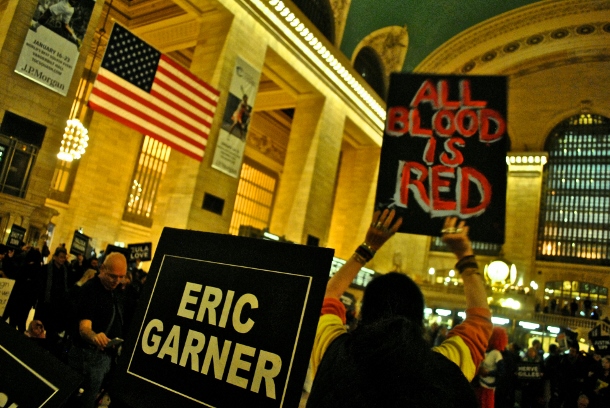 Activist holds up a sign reading "All Blood Is Red" in Grand Central on Martin Luther King Day. (WNV/Peter Rugh)