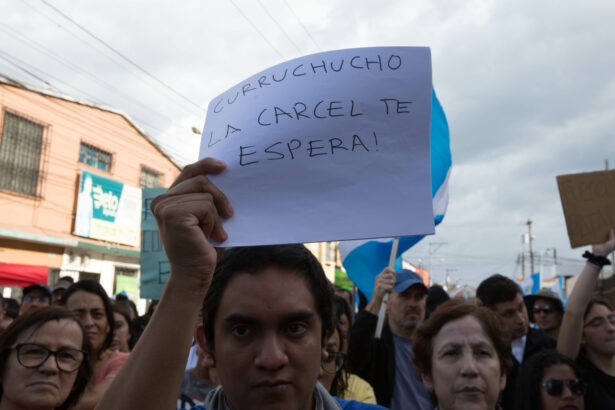 A man holds a sign that reads "Curruchiche, a prison cell awaits you" during a protest by Guatemalans to defend democracy