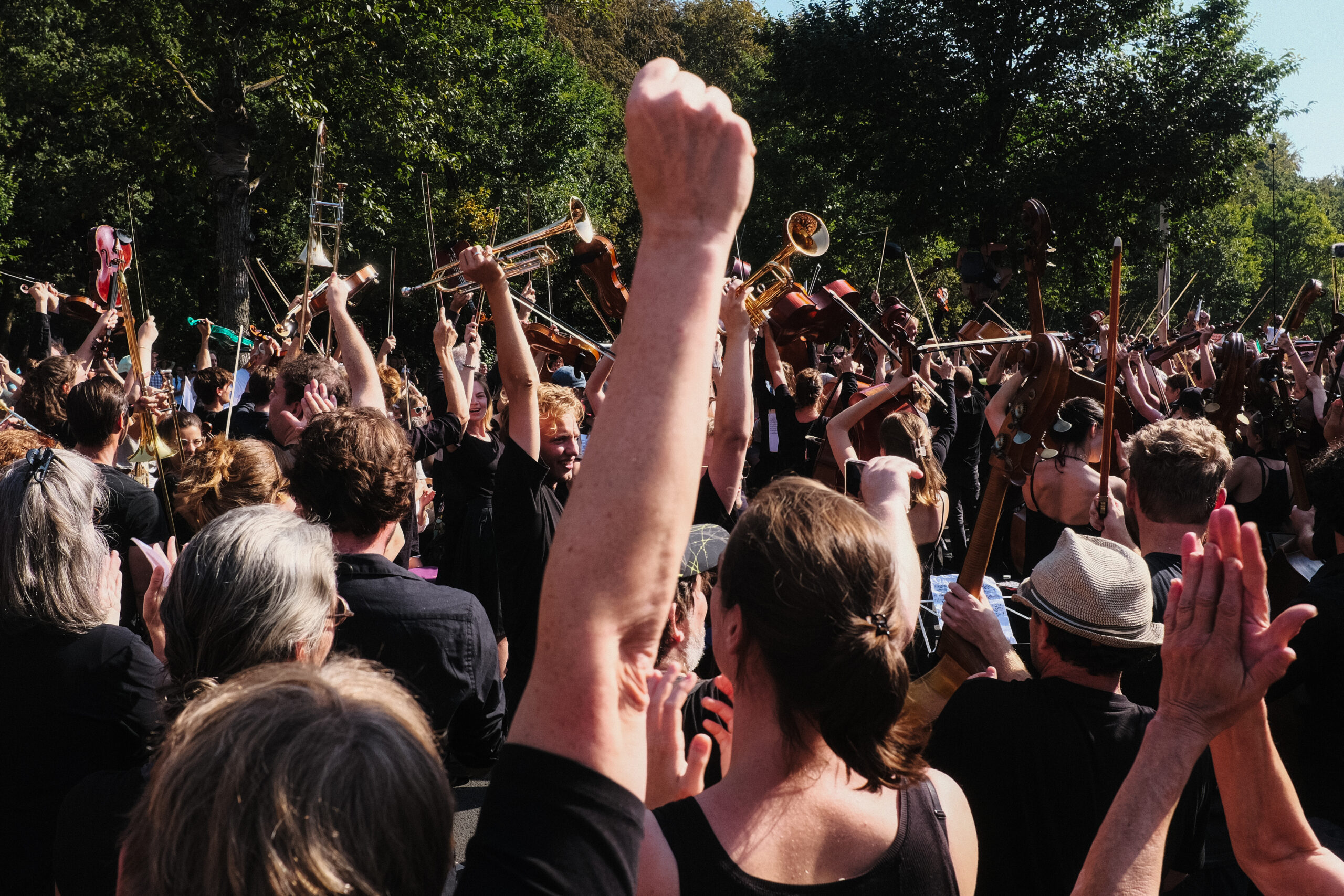 A crowd cheers after the A12 Orchestra performance, as instruments are held in the air