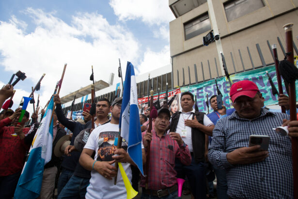 Ancestral Authorities raise their staffs while they sing Guatemala's National Anthem during protests outside the main offices of the country's embattled attorney general.
