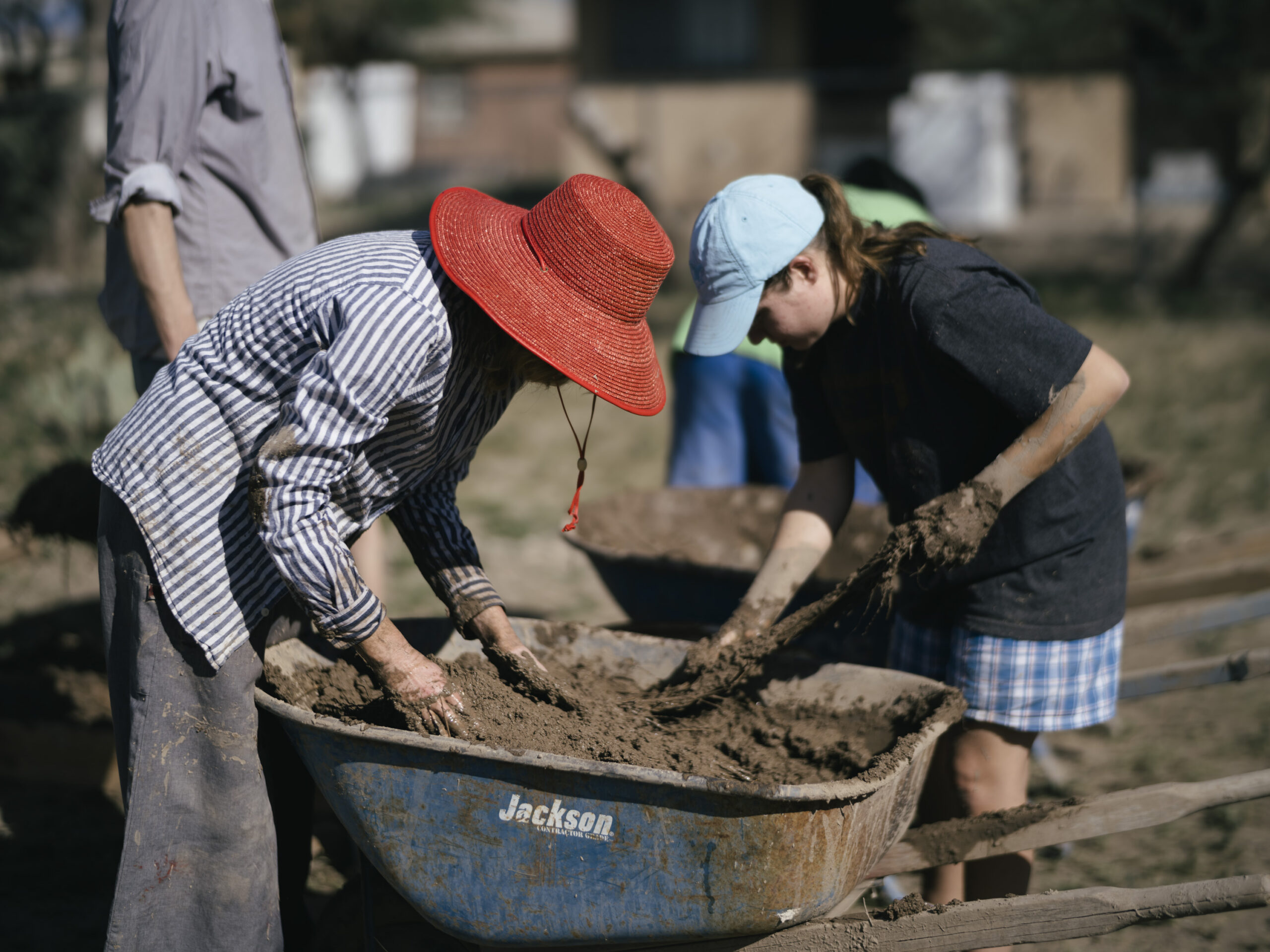 Volunteers mix harvested buffel grass with dirt and sand.