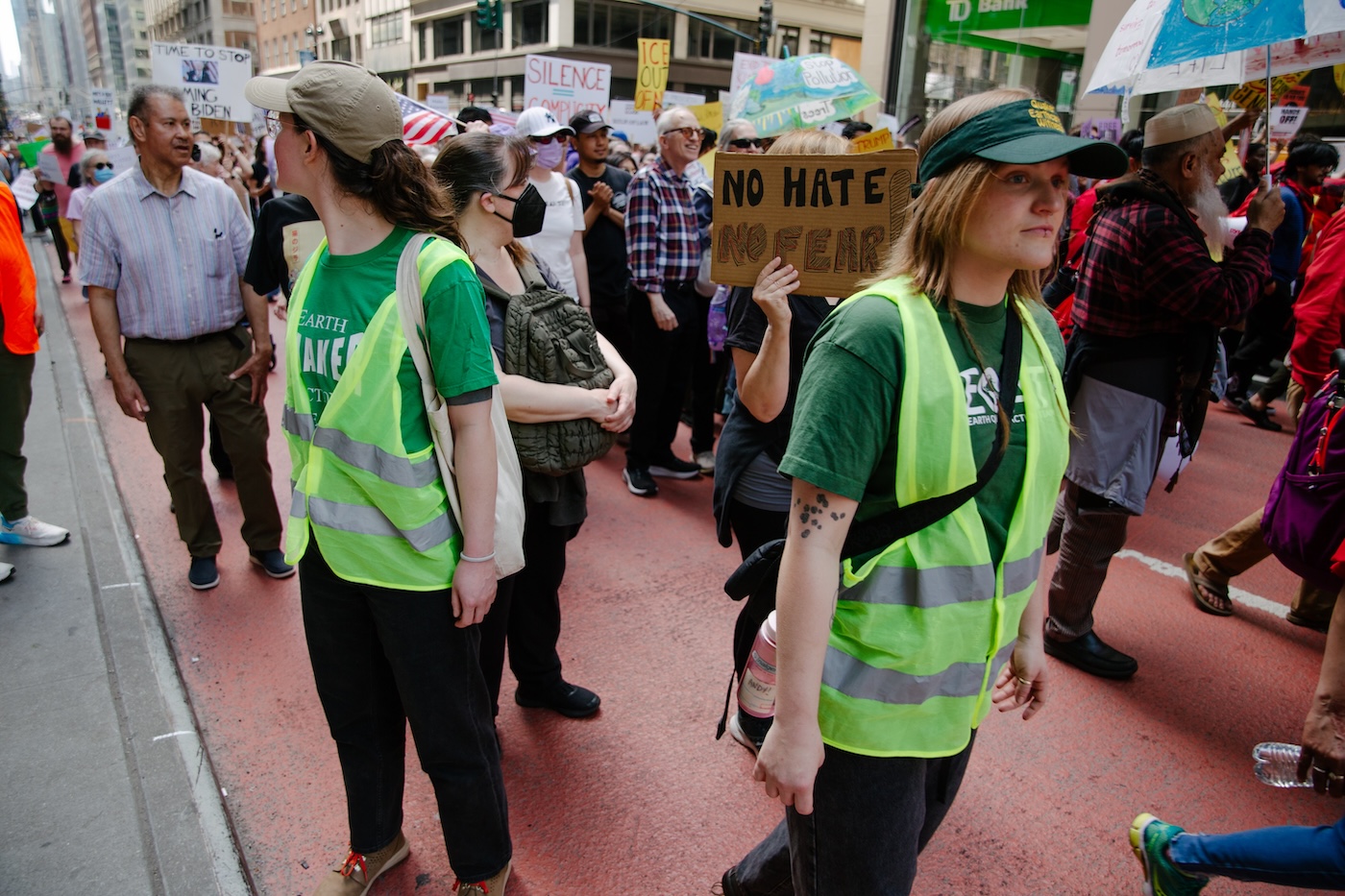 two people in yellow safety vests lead march in front of 